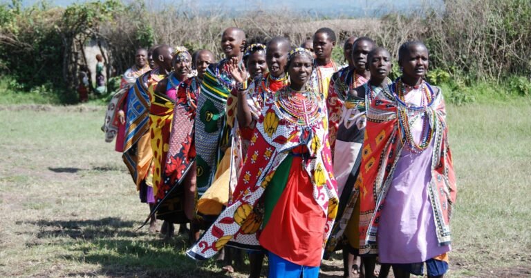 Group of Maasai women wearing traditional attire in a rural outdoor setting.
