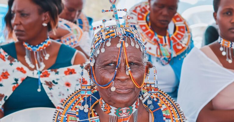 Women in vibrant traditional African clothing adorned with beaded jewelry and patterns.